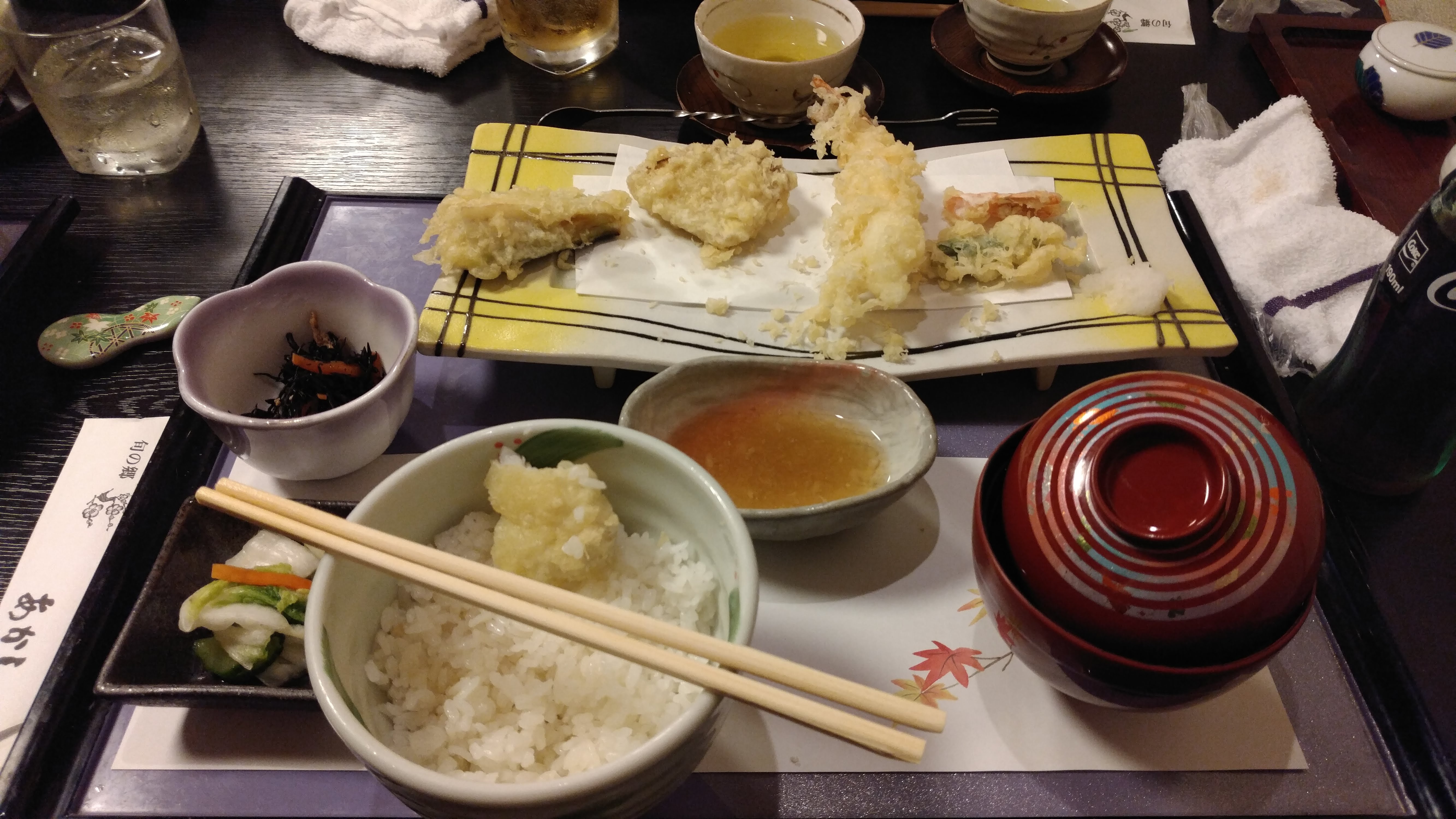 a tray of tempura and a bowl of rice with small bowls of greens, soup, and sauce