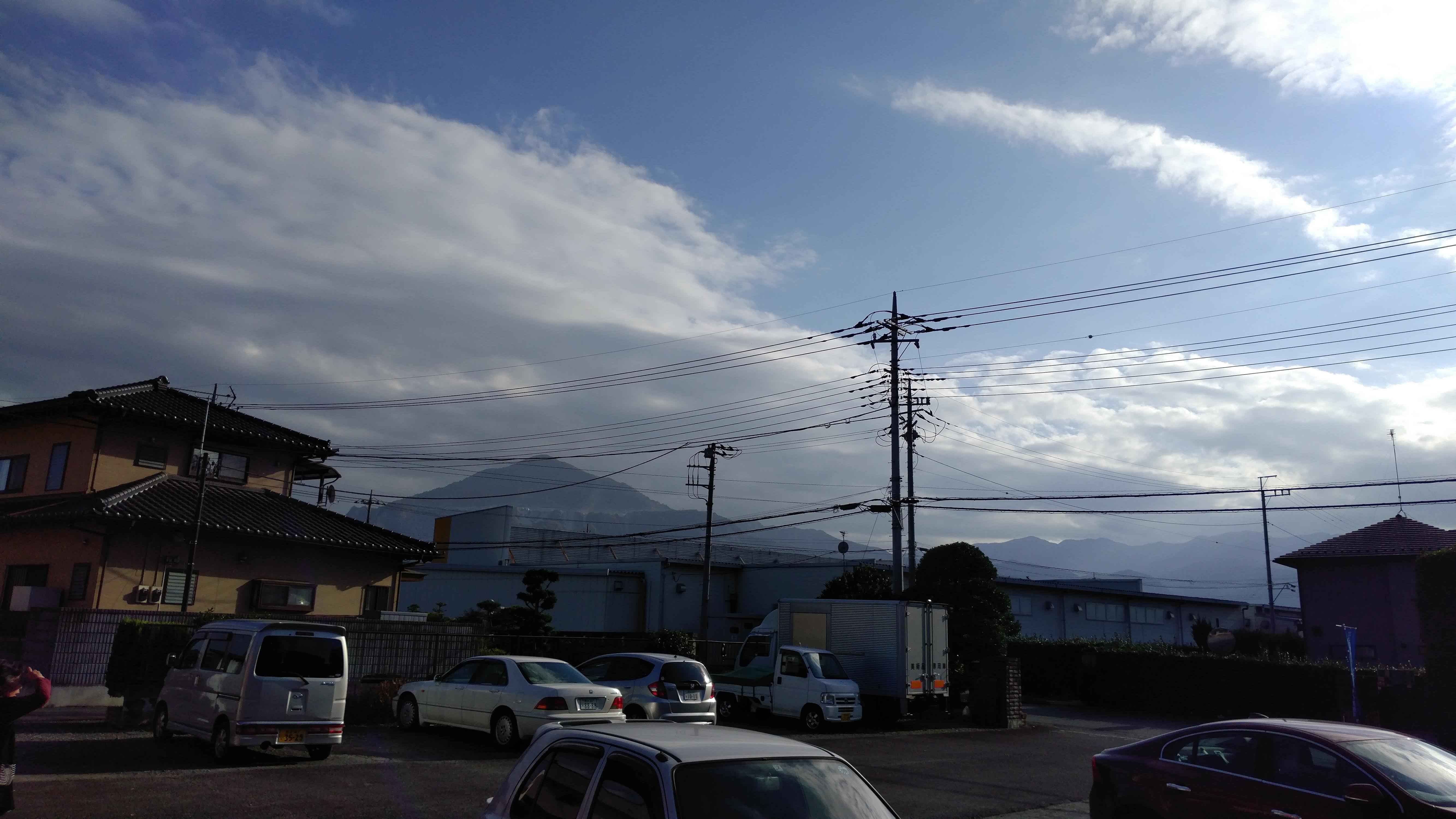 small japanese buildings with a blue partly cloudy sky and mountains in the distance