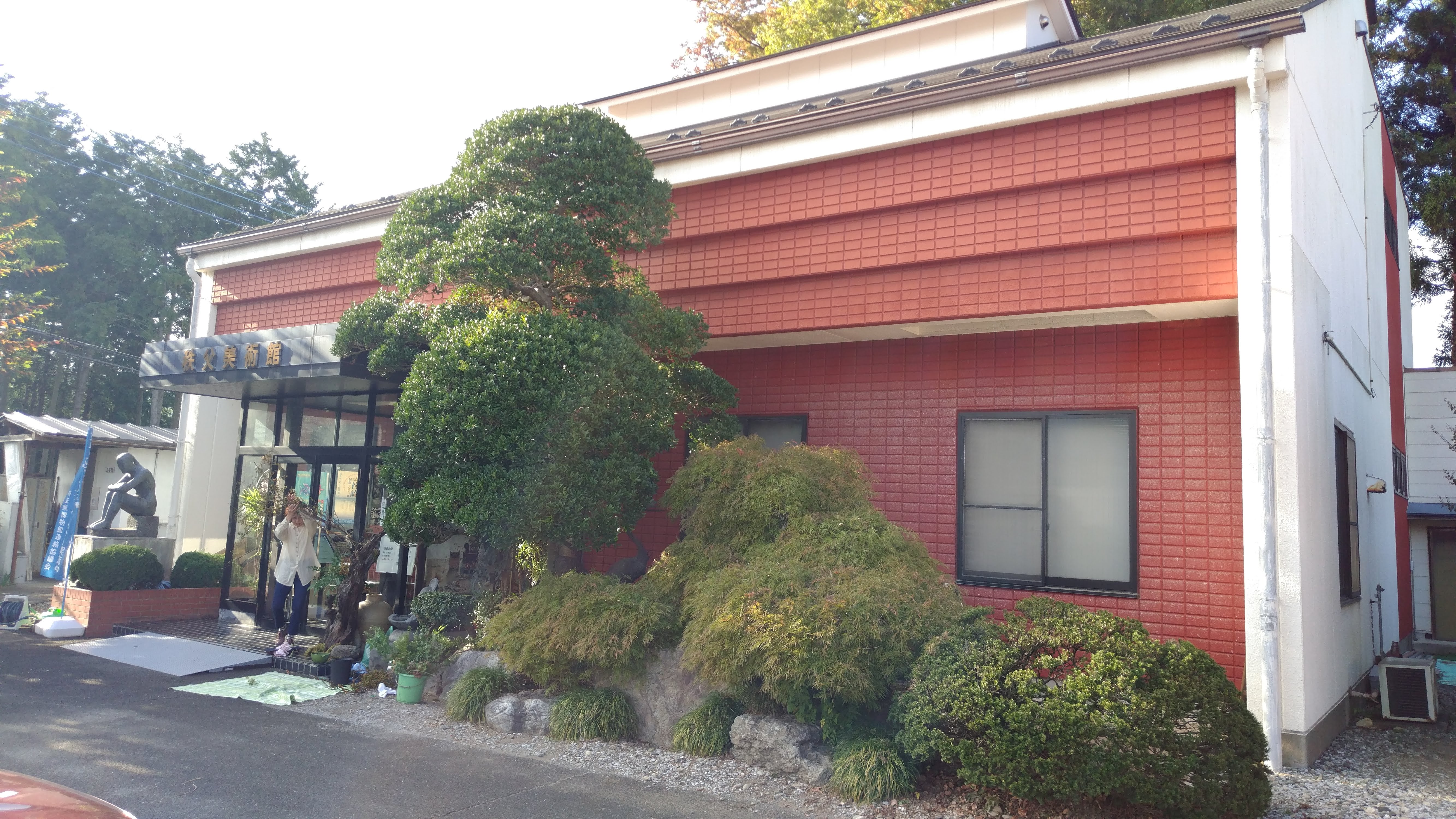a small reddish building with small manicured trees outside