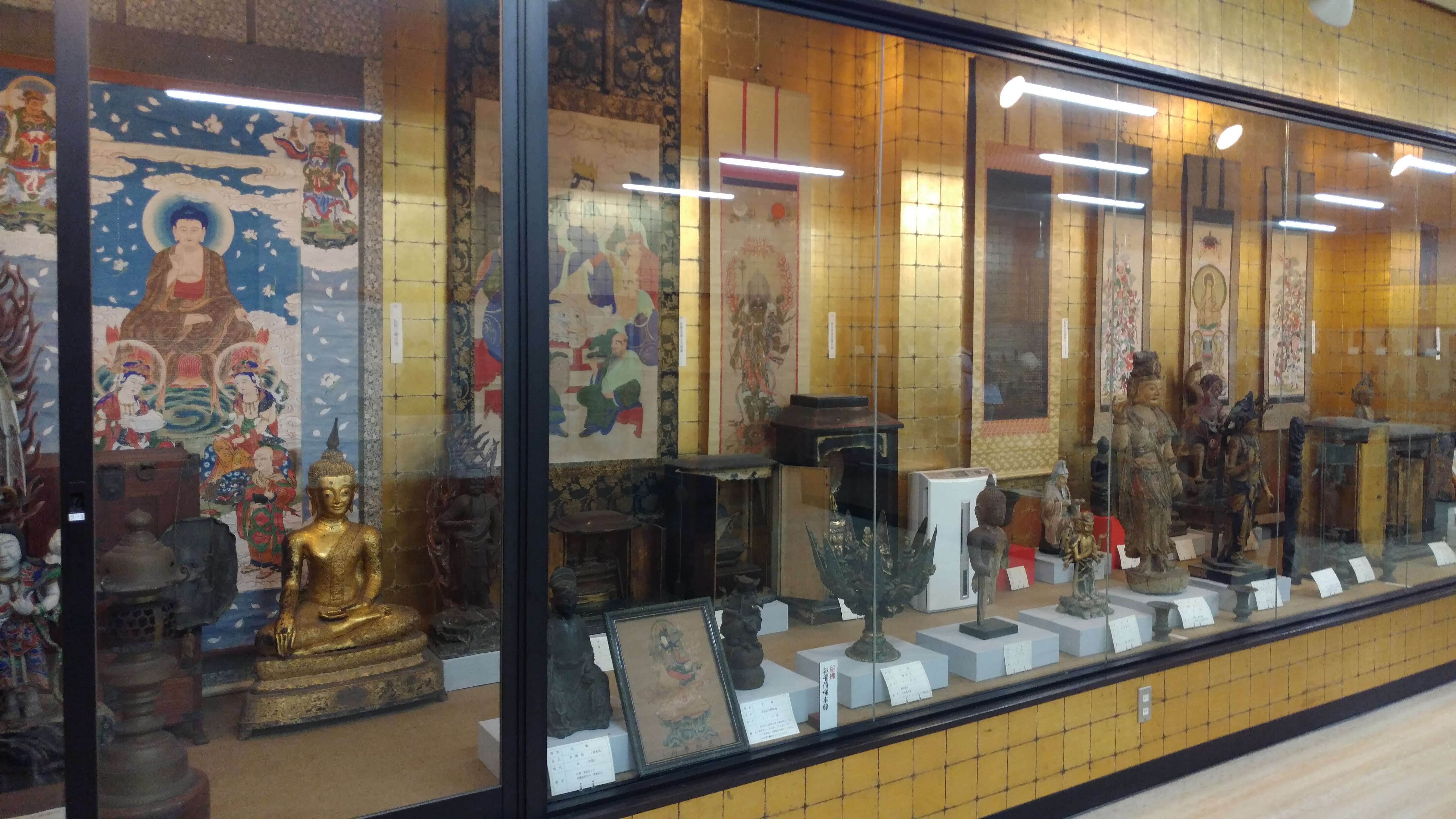 a large display case of asian artifacts lines a wall