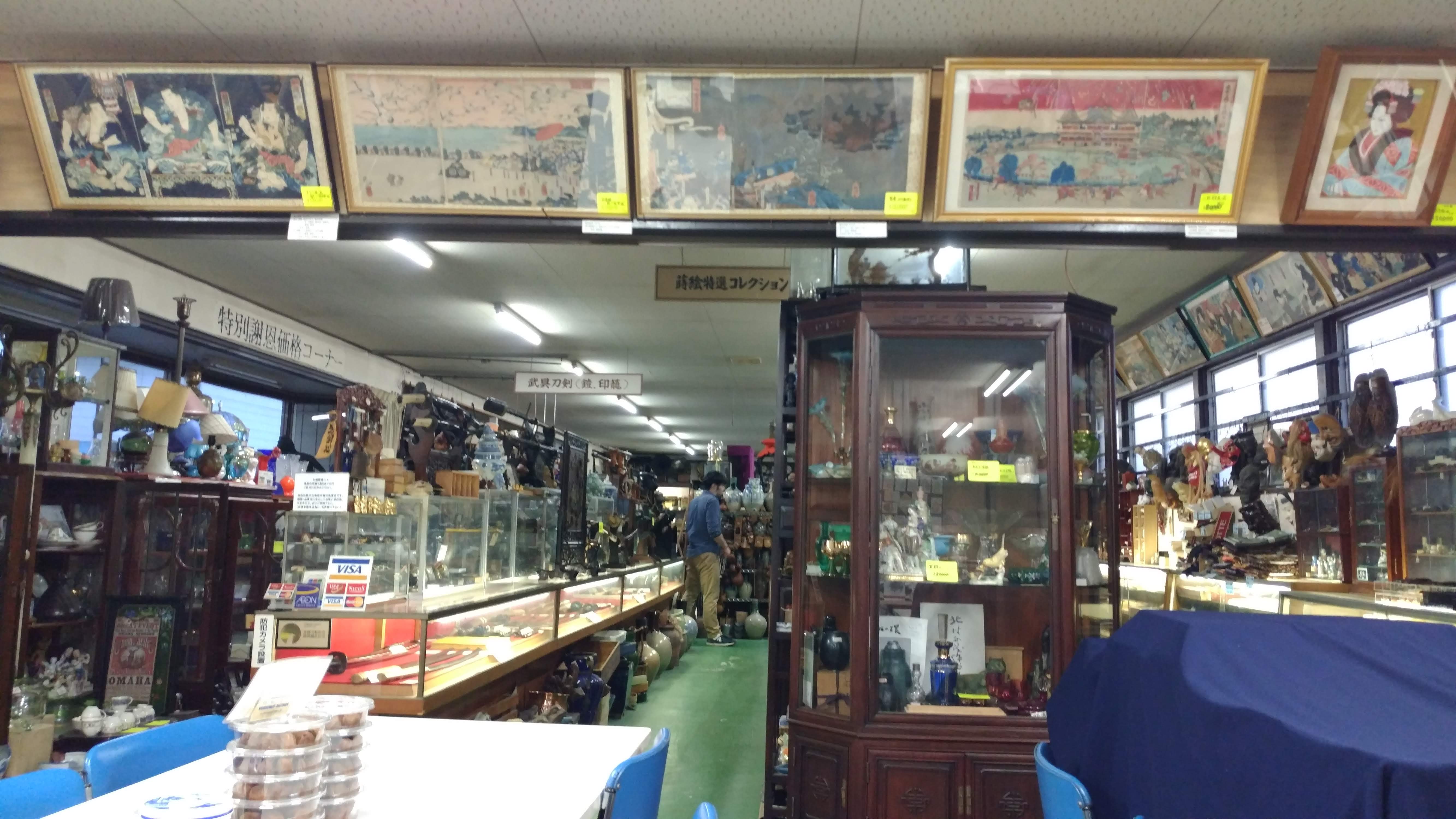 the shop interior with display cases running along the walls and down the middle.  Artwork is displayed on a ledge on the angled ceiling