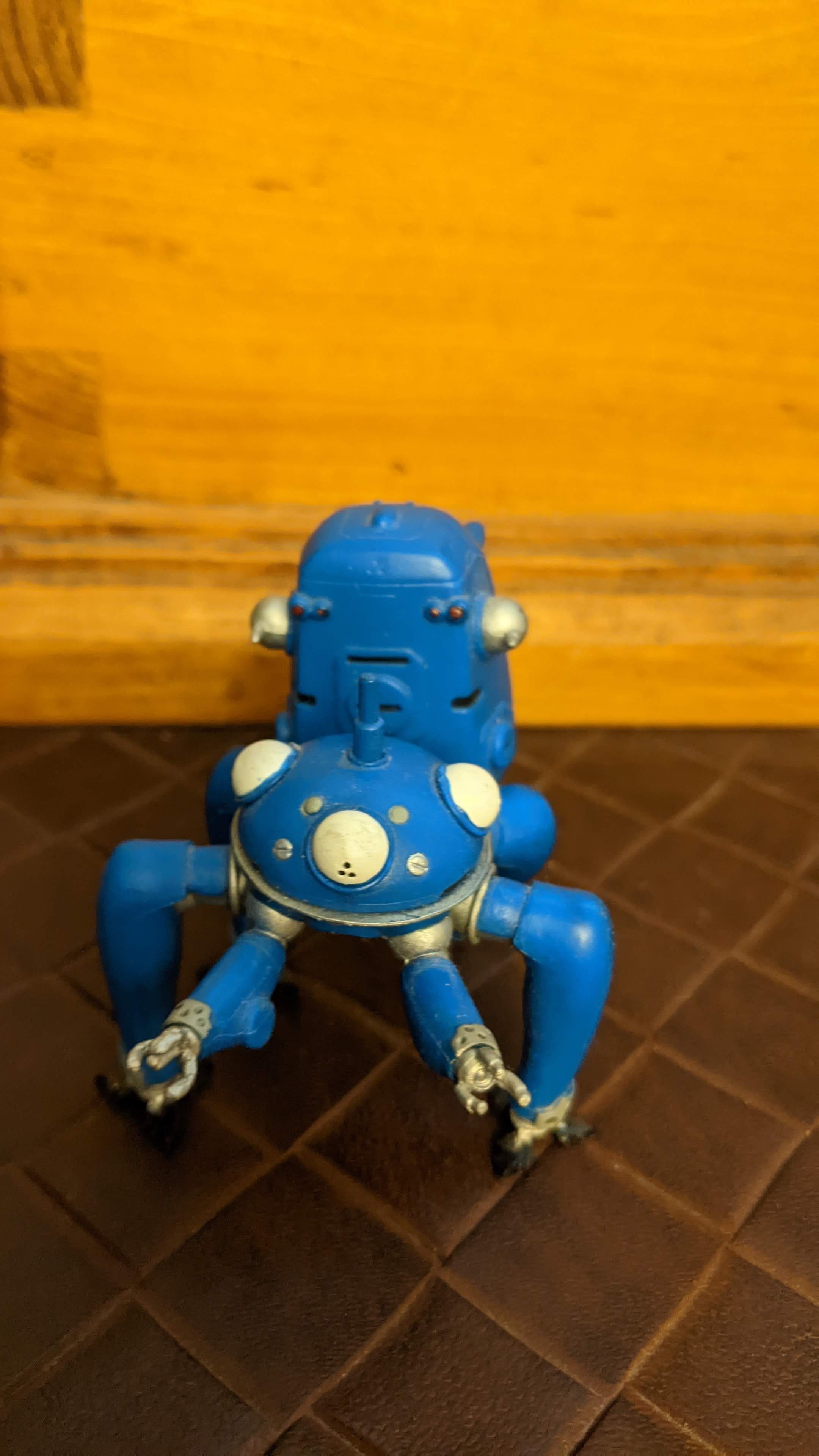 a blue six-legged robot toy in front of a wood box