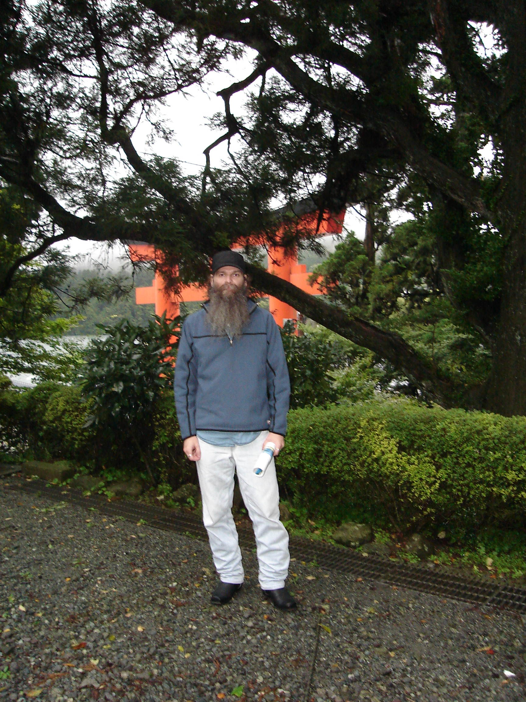 selfie in front of shrubs and trees with a the large torii gate partially visible in the background