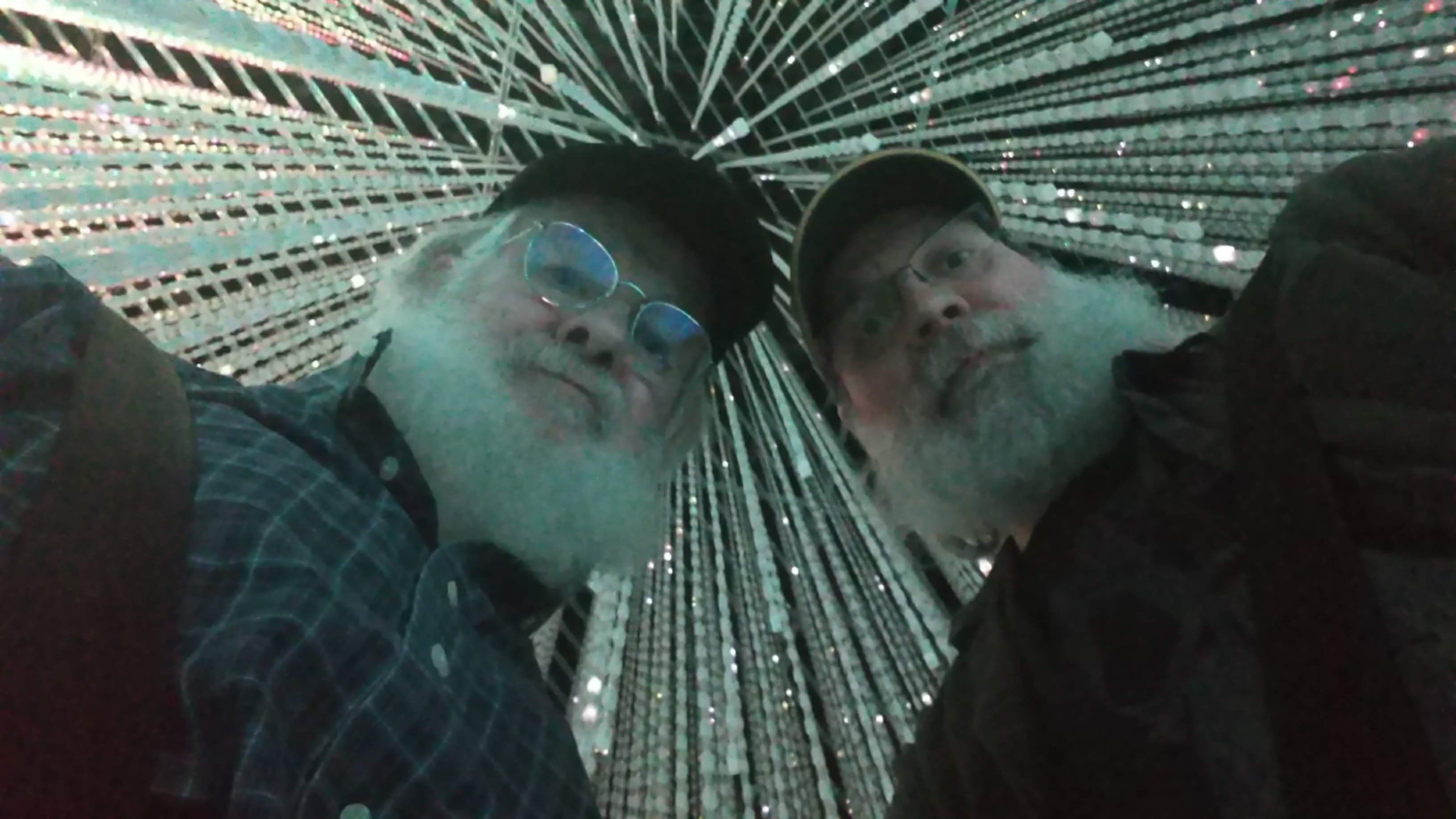 chris and earl look down at the camera the mirrored ceiling above them reflecting white lights into infinity