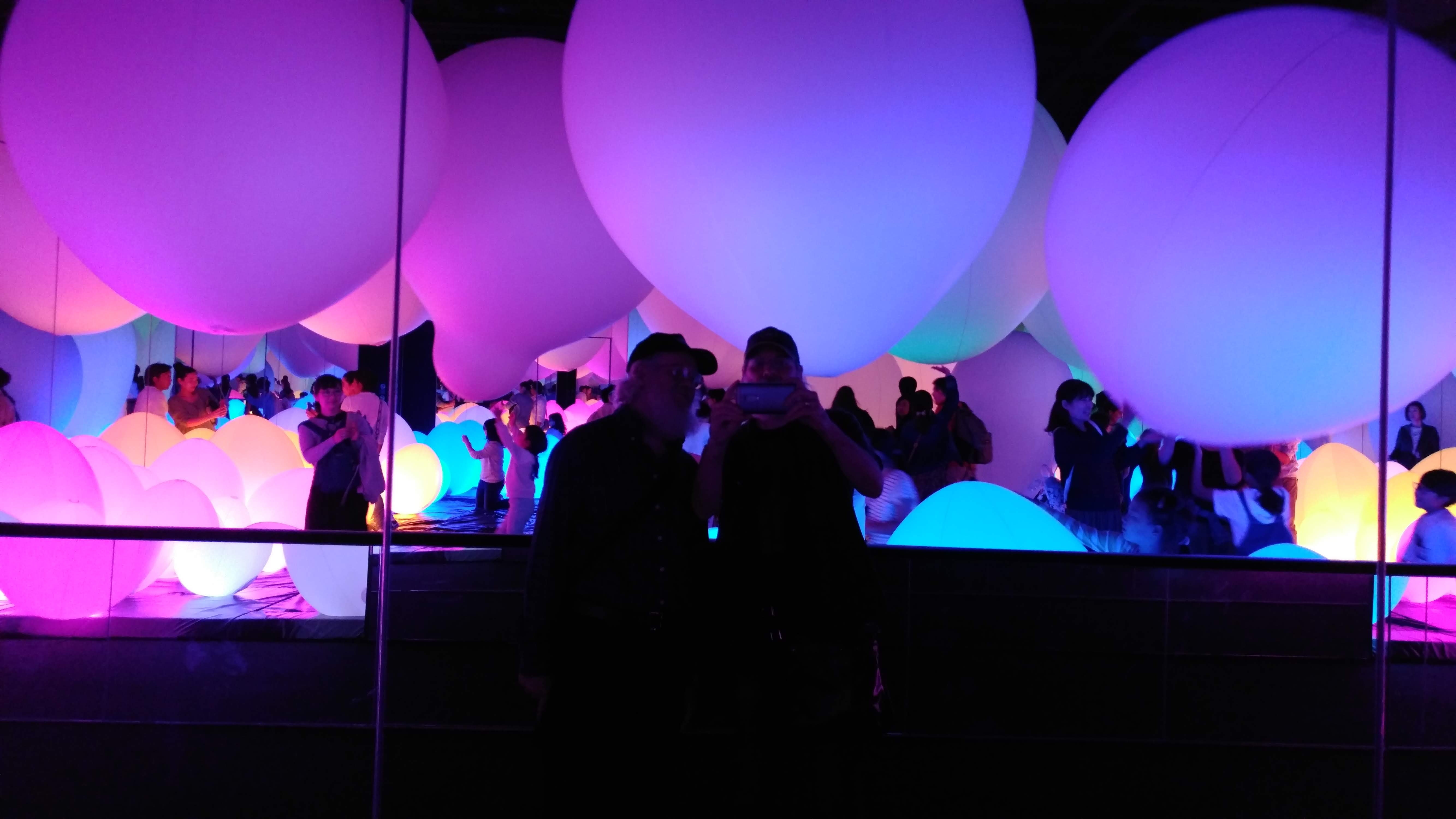 chris and earl reflected in a mirror in a room full of giant balloons