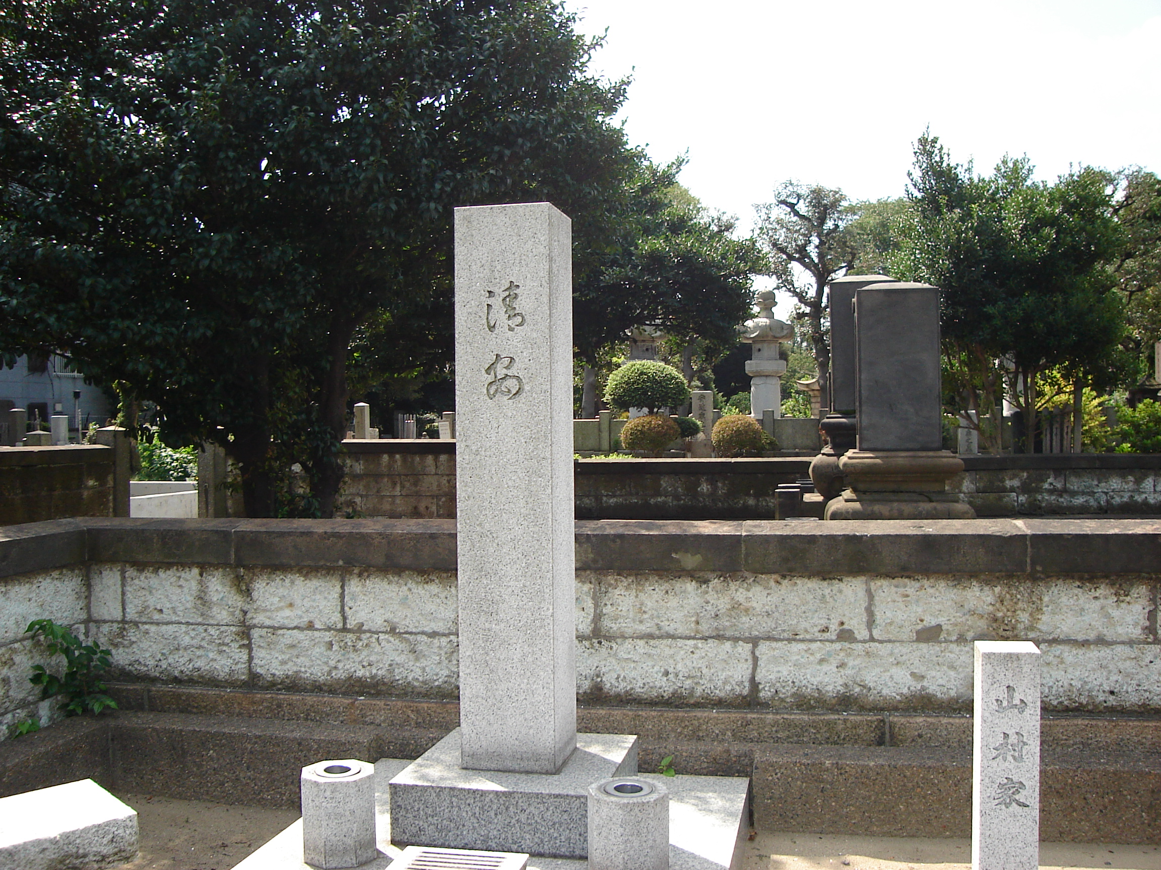 a tall rectangular gravestone engraved with japanese characters