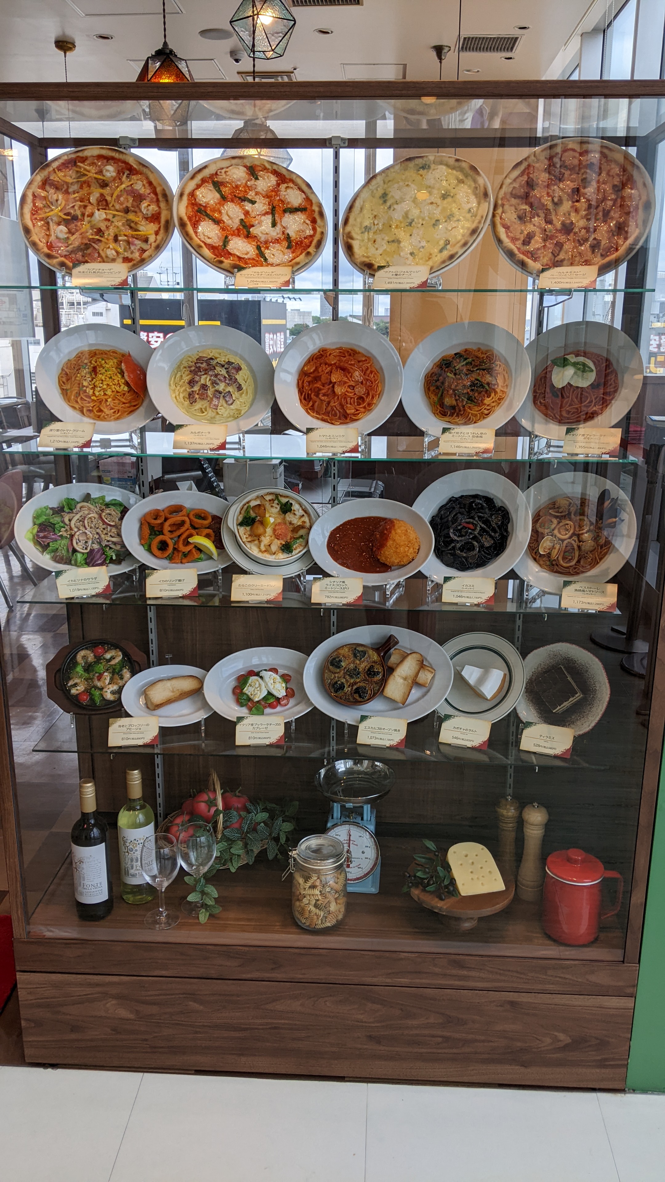 A display case of artificial food items of pizza and pasta
