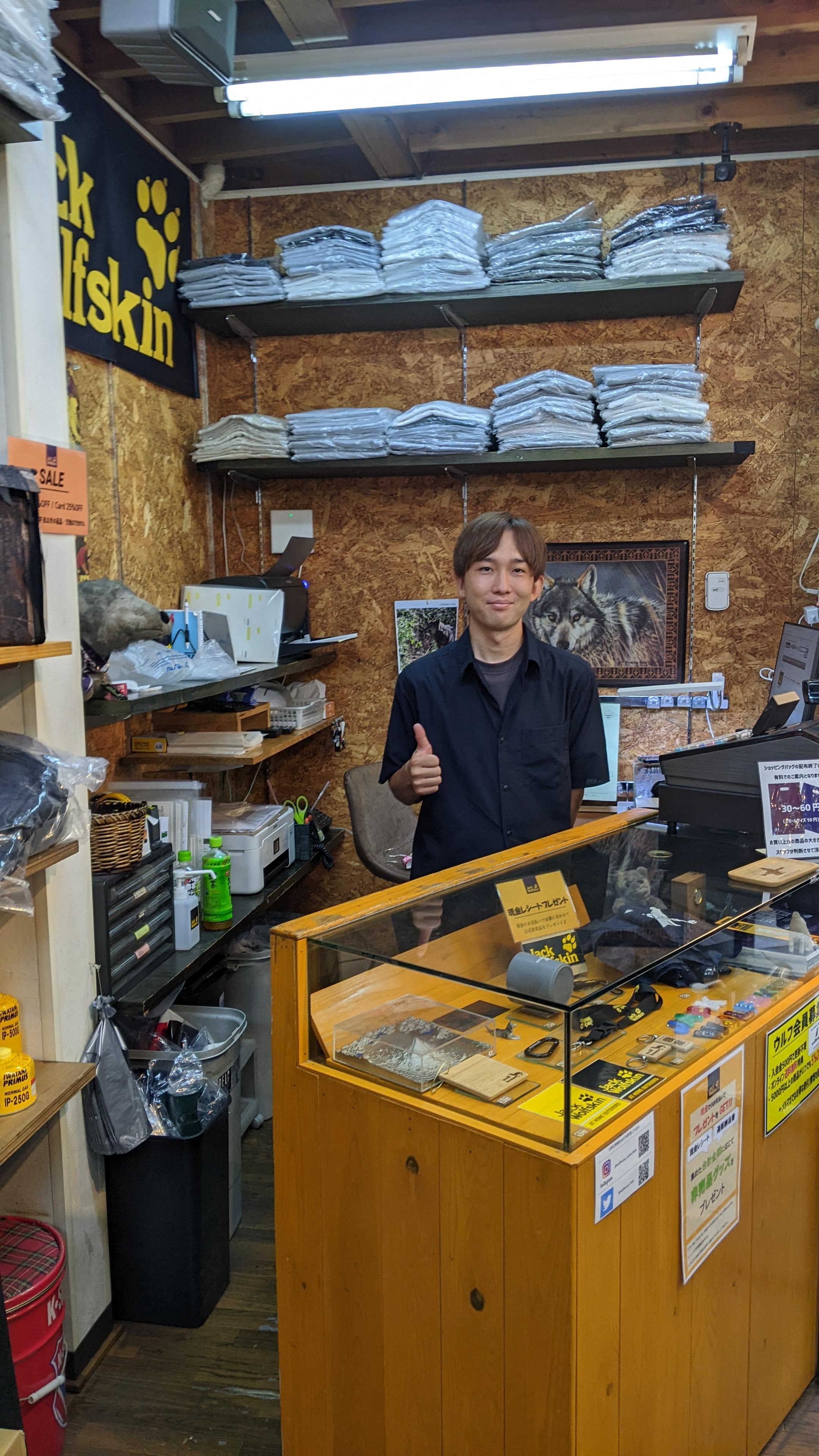 The cashier gives a thumbs up behind the counter