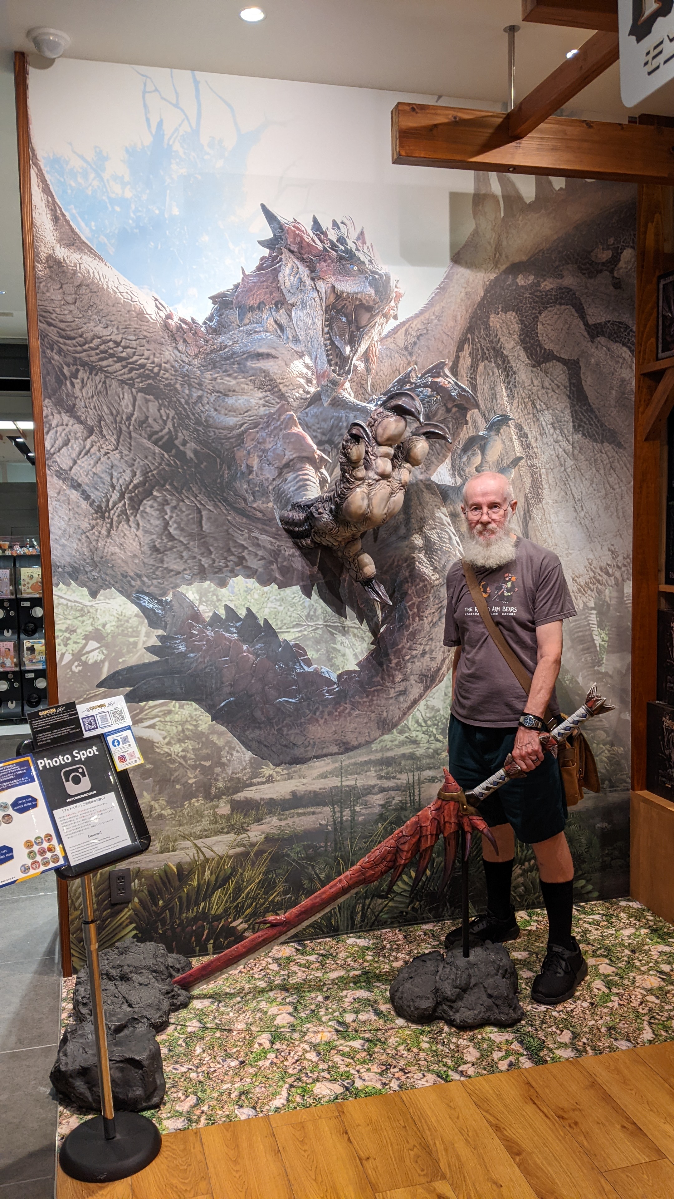 Chris holding a large fake sword in front of a dragon poster looking calm