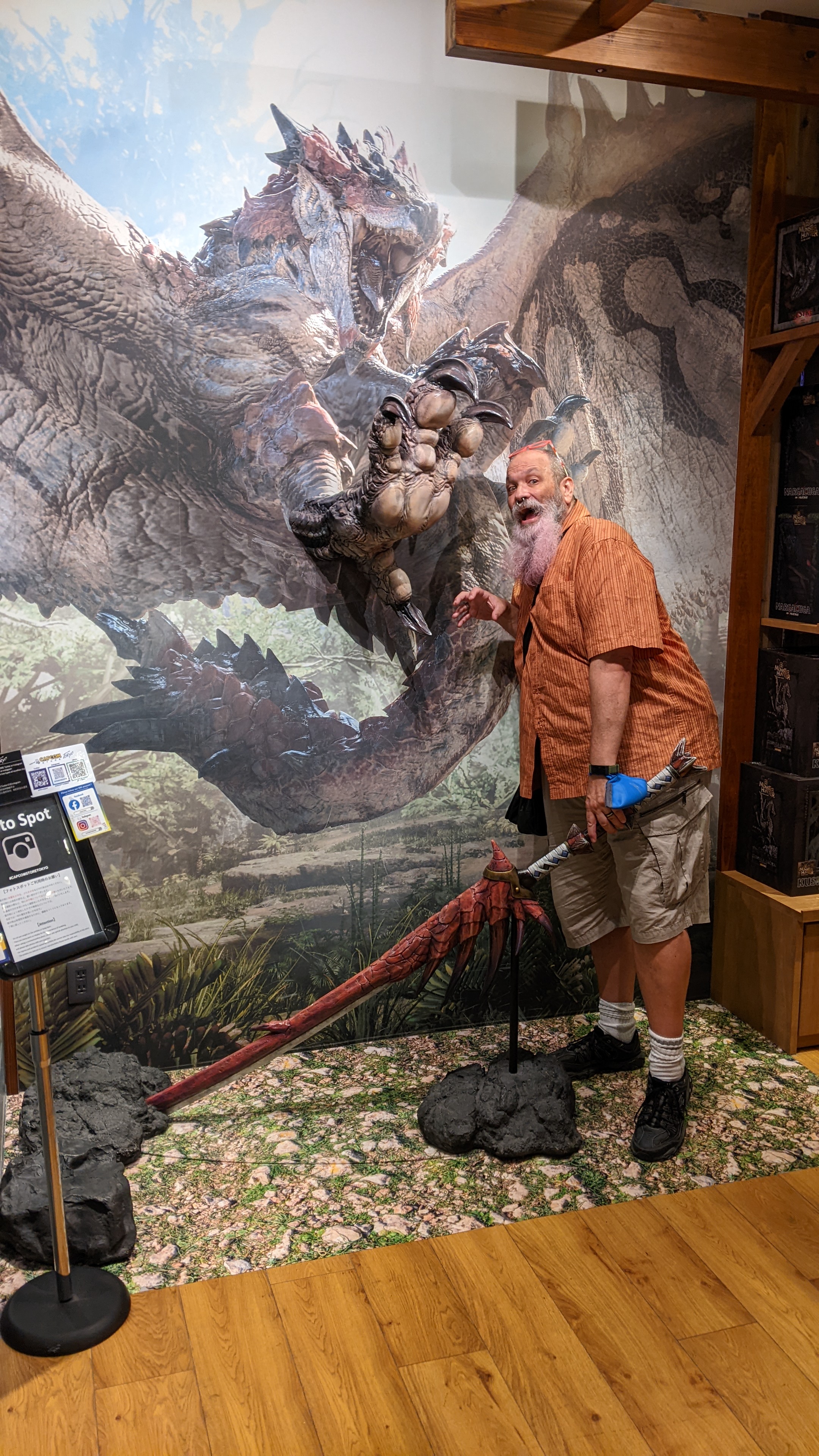 Les holding a large fake sword in front of a dragon poster looking scared