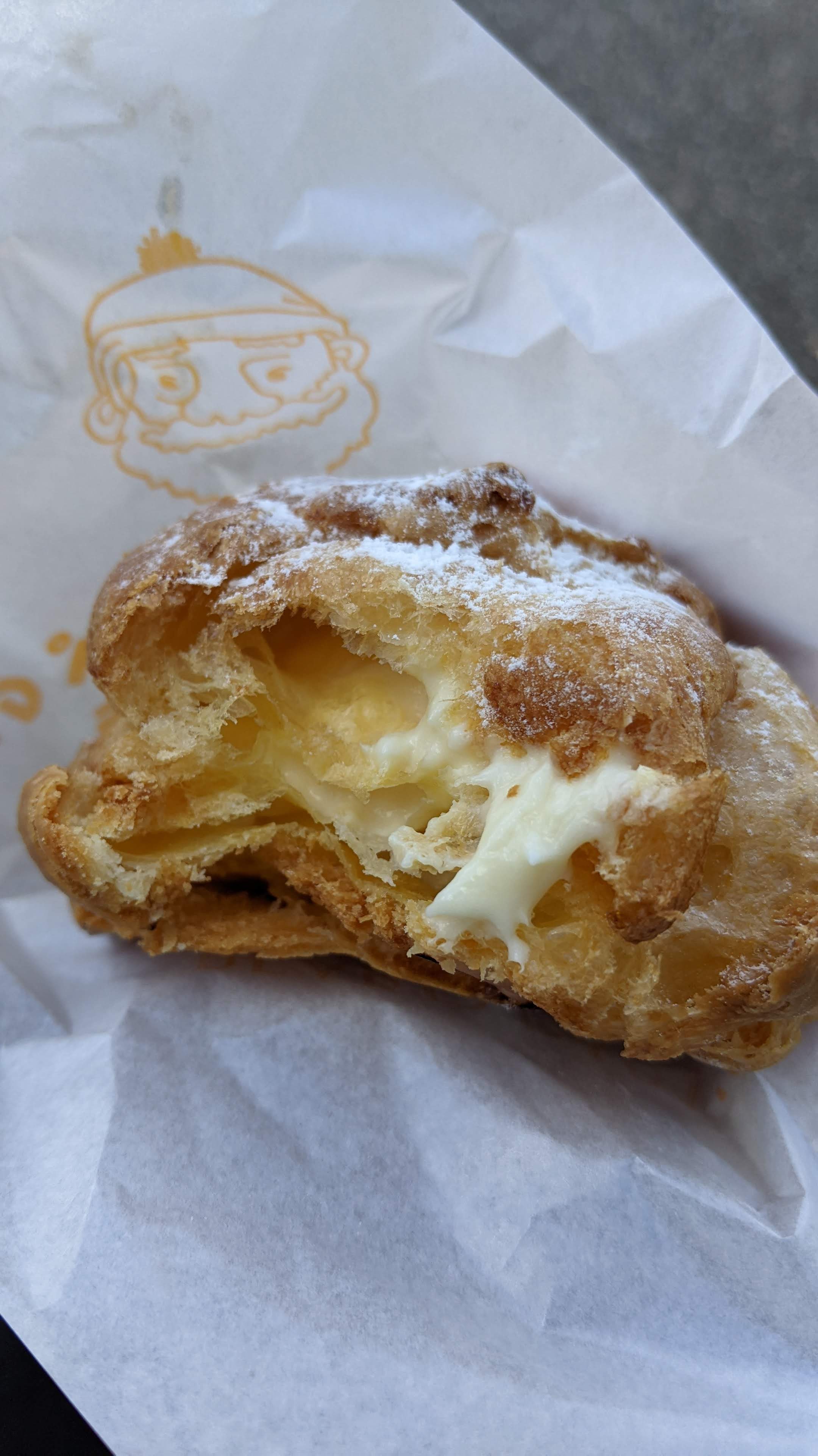 A Beard Papa creme puff with a bite taken out of it