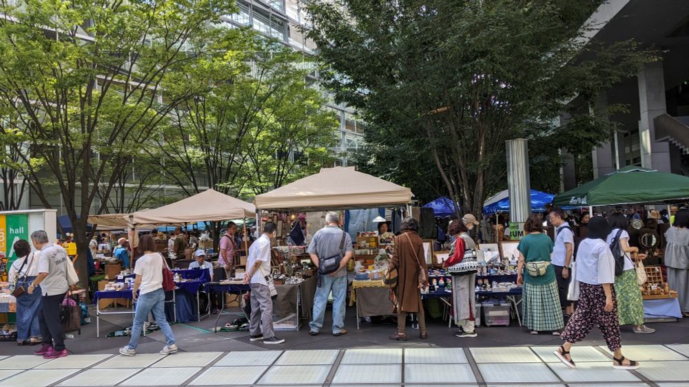 People shopping at covered booths in the sun