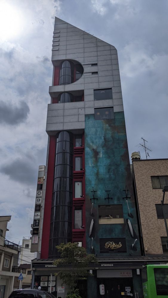 A tall building with an angled roof and windows that resemble a tube